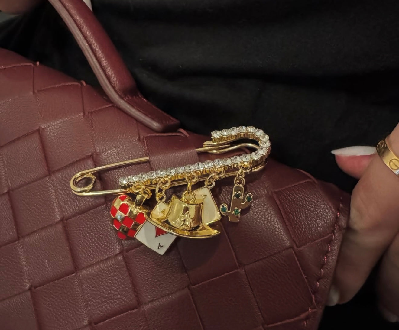 Gold bah pin with charms on a brown textured surface