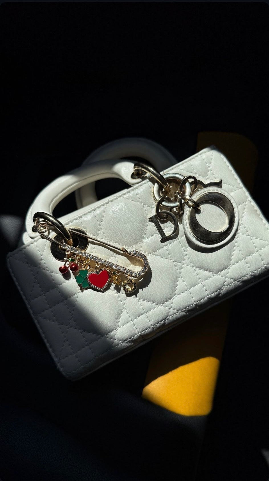 White handbag with decorative charms on a dark background